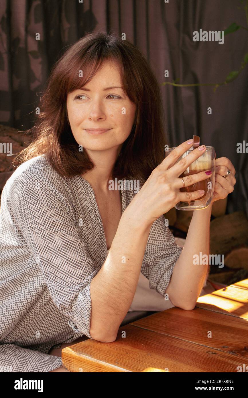 Hübsche Frau trinkt Kaffee im Straßencafé. Brünette mit Morgenkaffee. Authentischer Lifestyle. Ruhiges Morgenkonzept. Natürliche Schönheit der Frau. Stockfoto