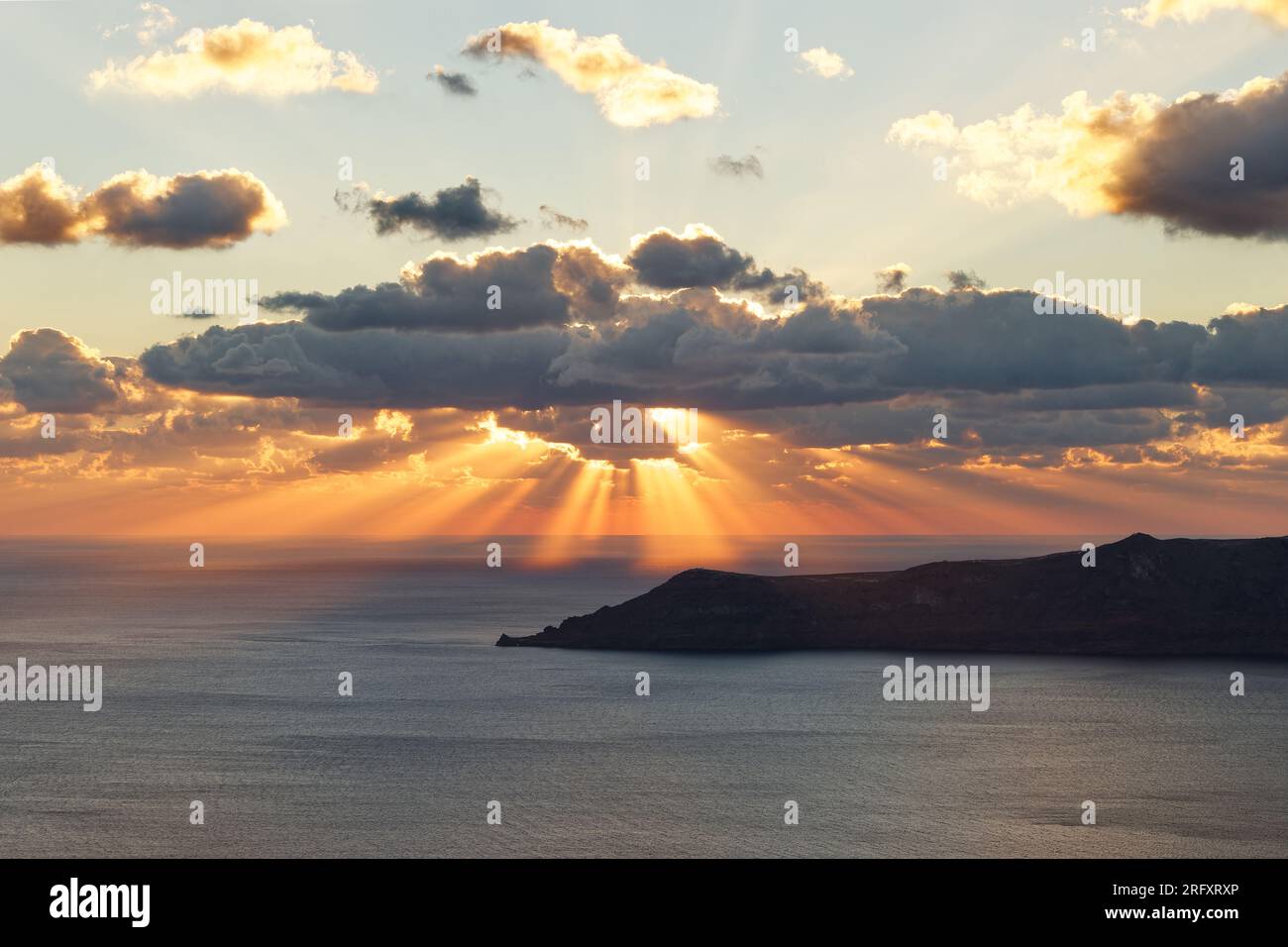 Stimmungsvoller Sonnenuntergang am Meer mit Sonnenstrahlen in Orange, Wolken vor der Sonne erzeugen deutlich sichtbare Lichtstrahlen und Schatten Stockfoto