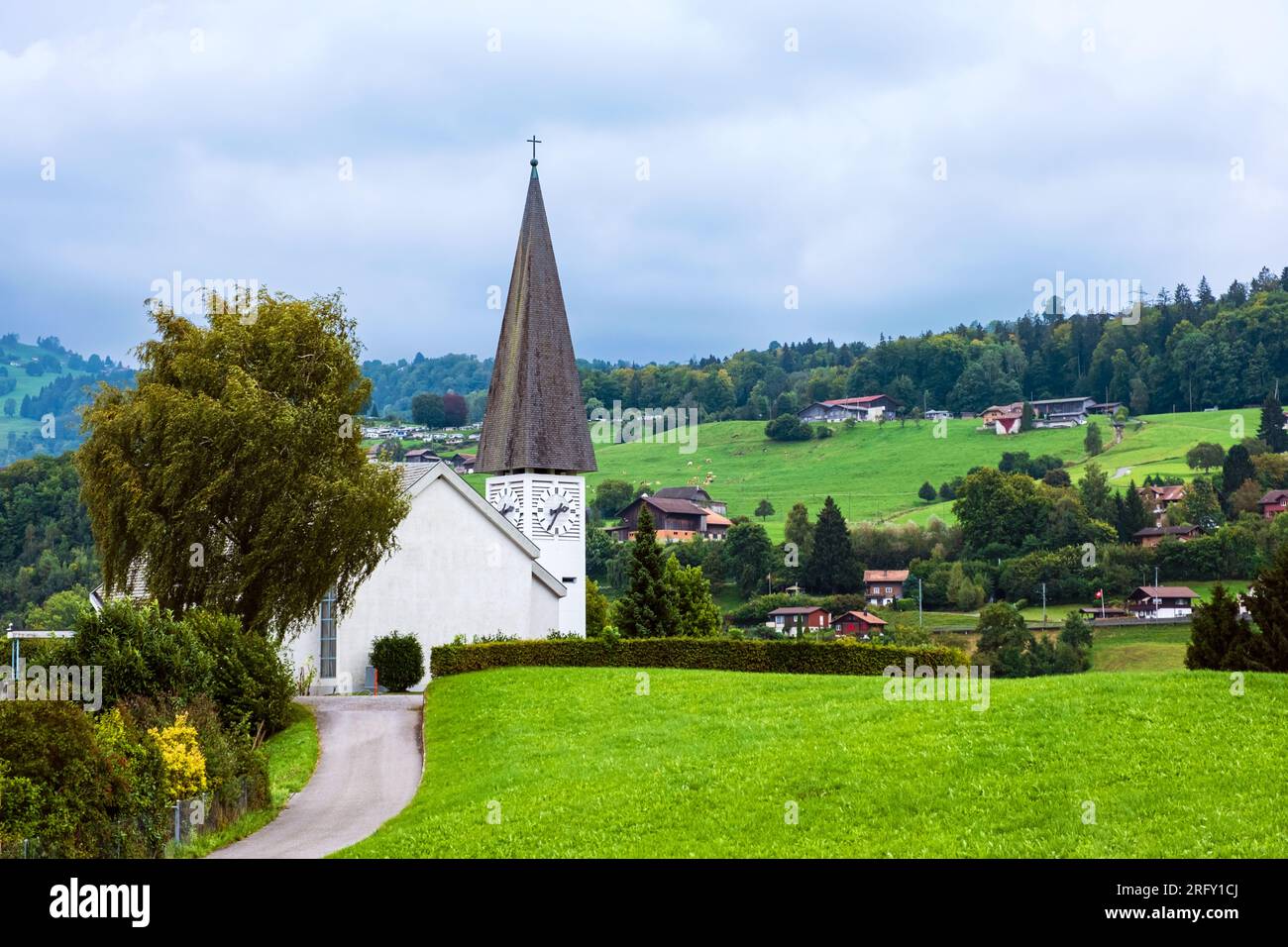 Faulensee-Dorf mit weißer Kirche und typischen schweizer Häusern auf Hügeln nahe Spiezstadt am Thunersee im Berner Oberland im Kanton Bern Stockfoto