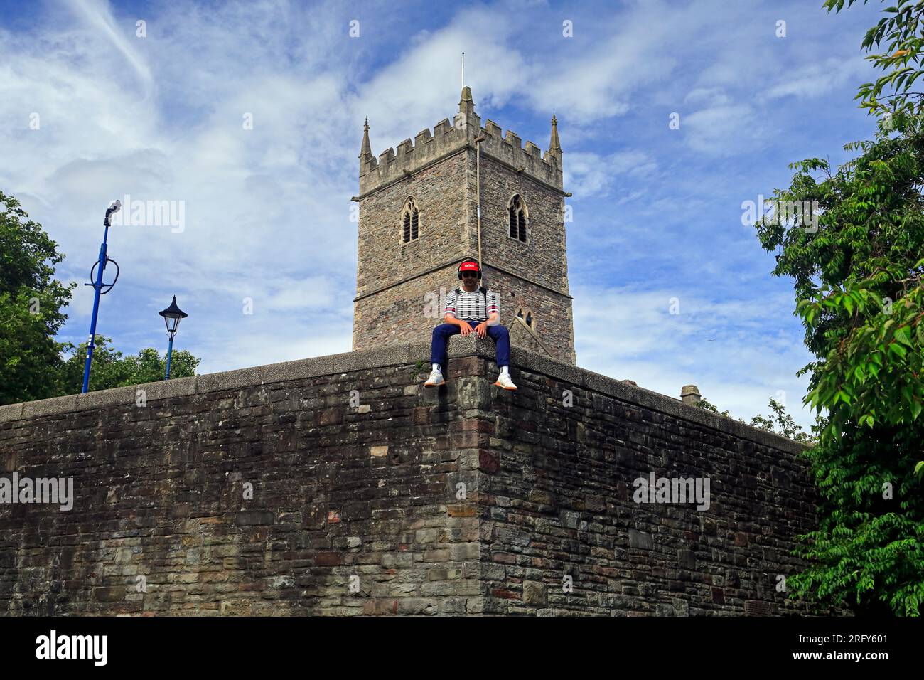Mann in gestreiftem Pullover mit Malboro-Hut, sitzt auf einer hohen Mauer in der Peterskirche, Burgberg, mit Überwachungskamera Stockfoto
