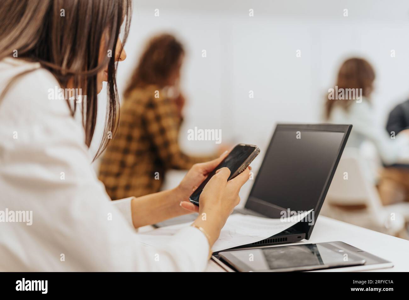 Die Frau nutzt ihr Mobiltelefon für geschäftliche Zwecke, wie z. B. Anrufe tätigen, E-Mails senden und ihren Kalender überprüfen Stockfoto