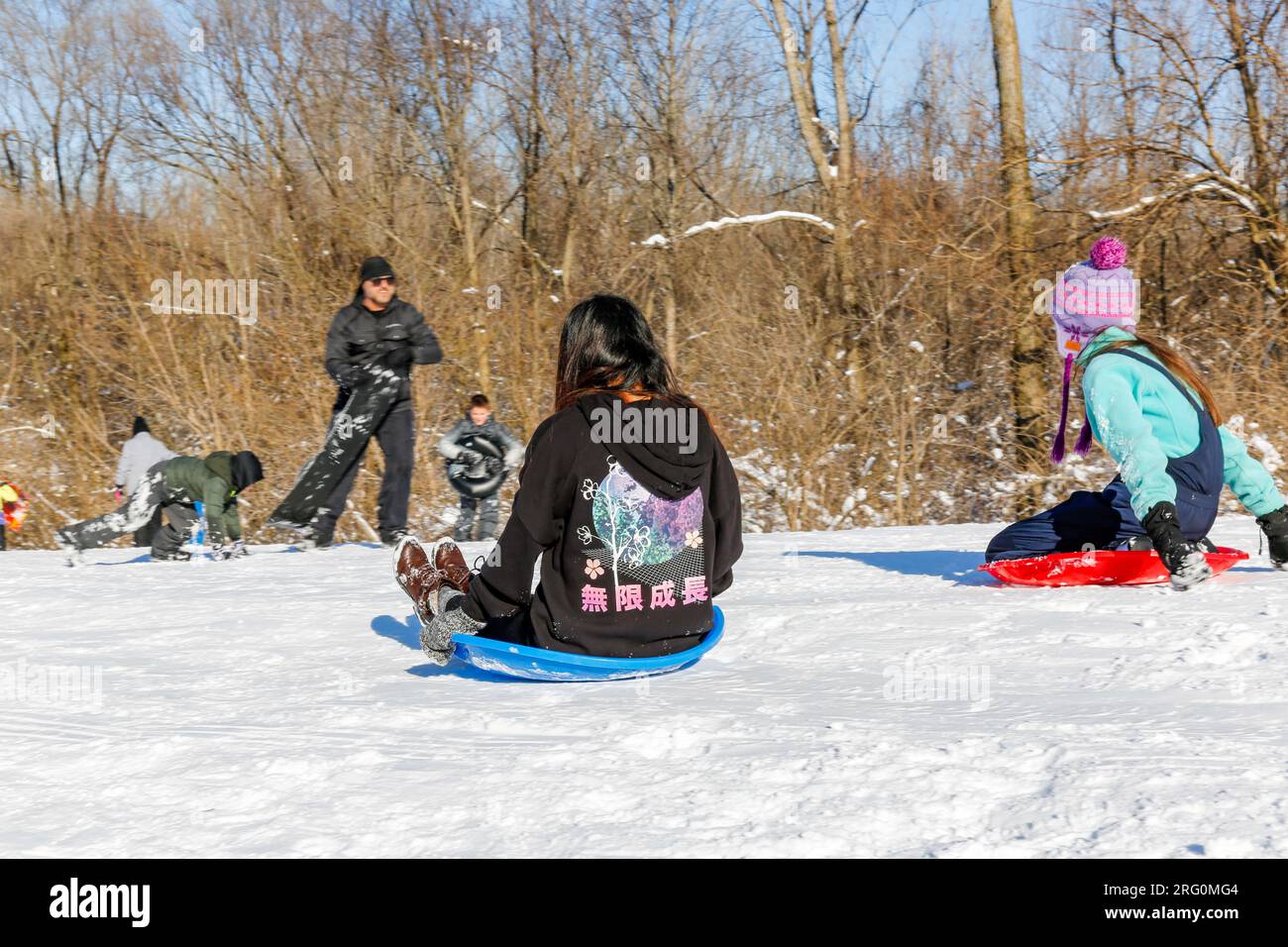 Zwei Mädchen fuhren im Metea County Park in der Nähe von Fort Wayne, Indiana, USA, einen Hügel auf Plastikscheiben hinunter. Stockfoto