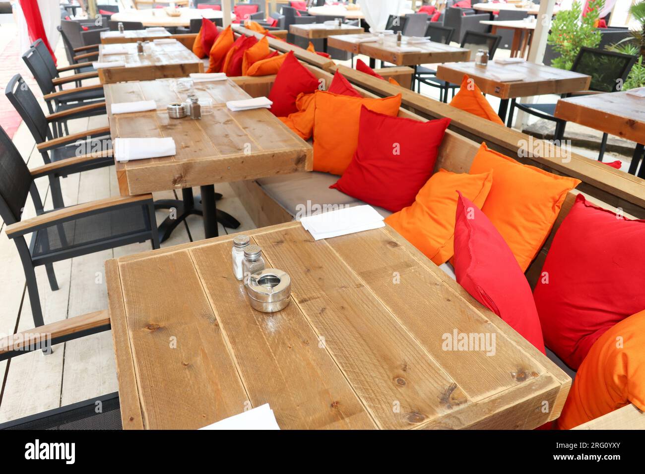 Terrasse eines Restaurants im Sand mit roten und orangefarbenen Kissen Stockfoto