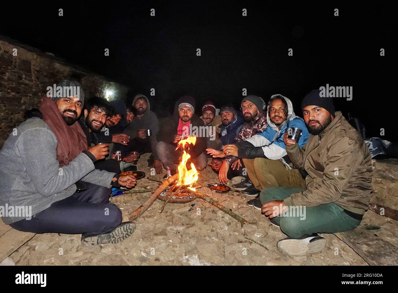Oktober 14. 2022, Uttarakhand Indien. Trekker-Freunde genießen das Winterfeuer mit Snacks und Tee während des Outdoor-Abenteuers. Camping und Trekking in der Landschaft Stockfoto