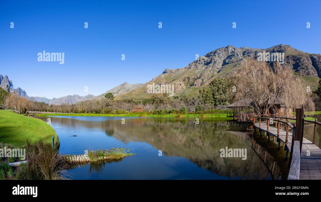 Malerischer Blick über das Wasser des Sees, die Talberge, die Schneepisten im blauen Himmel. Stockfoto