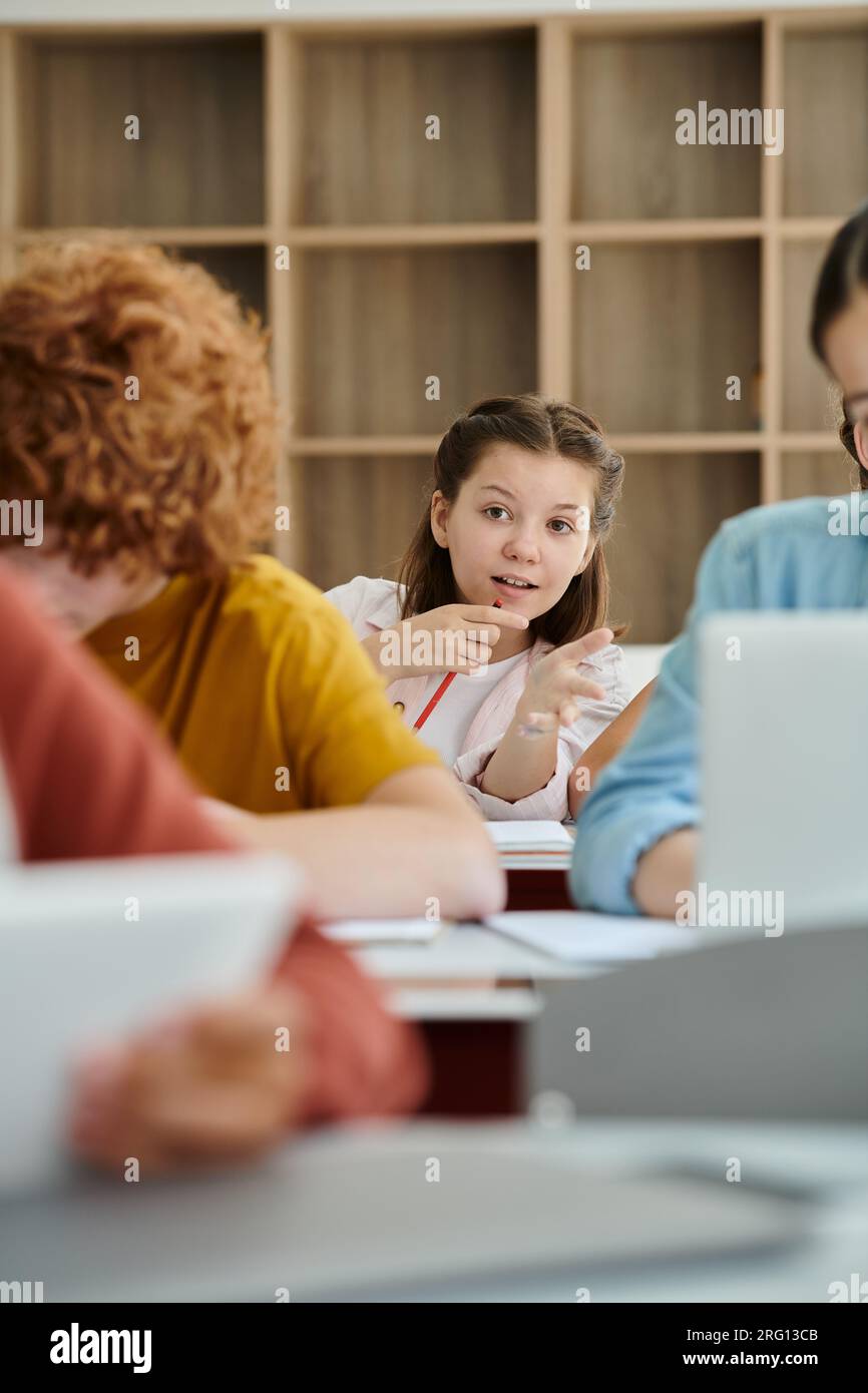 Teenager-Schülerin, die während des Unterrichts mit dem Finger auf verschwommene Klassenkameraden zeigt Stockfoto