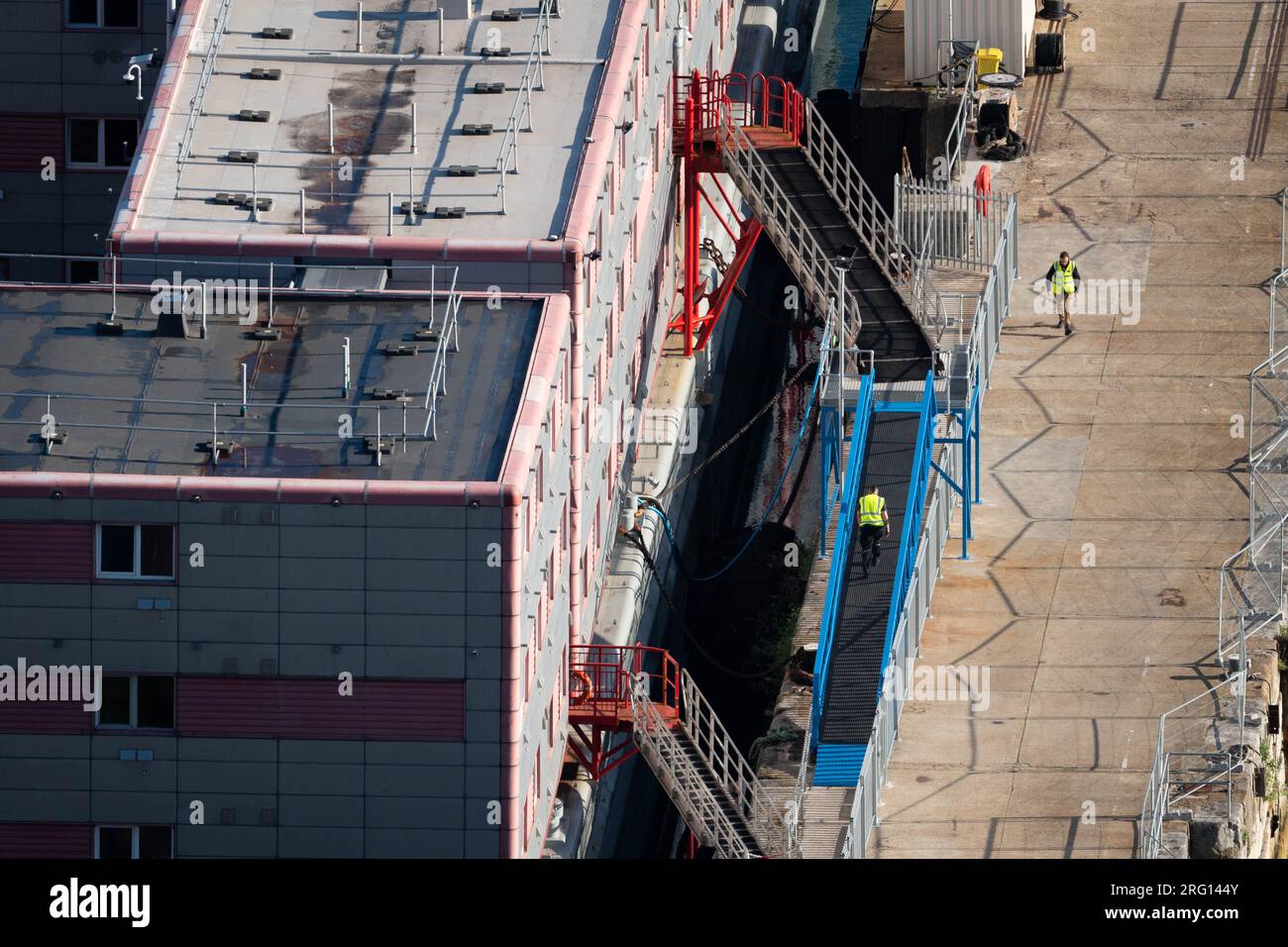 Arbeiter auf dem Unterkunftsschiff Bibby Stockholm im Hafen Portland in Dorset, das bis zu 500 Personen aufnehmen wird. Das Innenministerium hat gesagt, dass etwa 50 Asylbewerber an Bord des Bibby Stockholm gehen würden, wobei die Zahl in den kommenden Monaten trotz der von einigen konservativen Abgeordneten und Einheimischen geäußerten Sicherheitsbedenken auf ihre maximale Kapazität ansteigen würde. Foto: Montag, 7. August 2023. Stockfoto