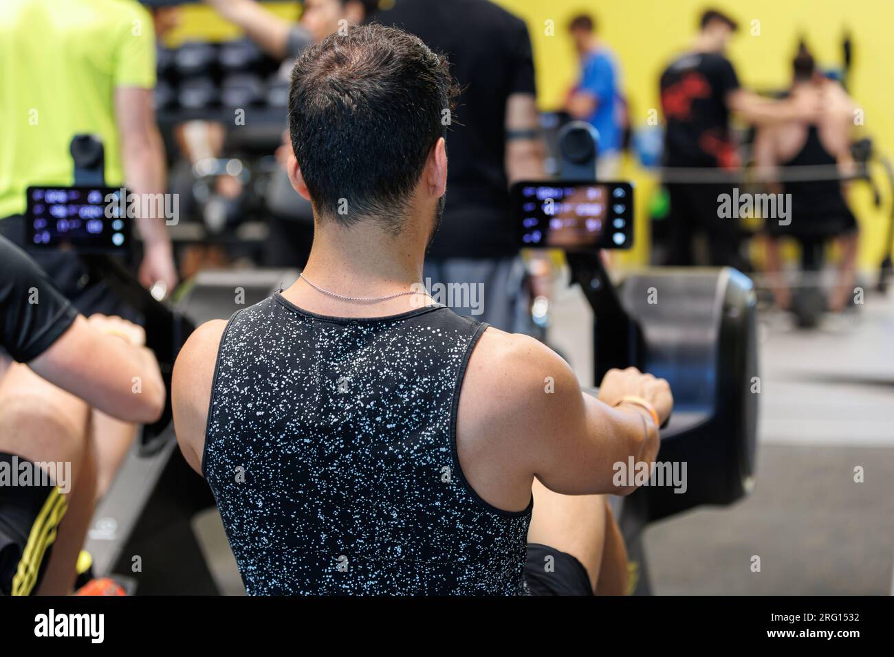 Sportler-Übungen am Rudergerät im Fitnessstudio: Fitnessgeräte. Stockfoto