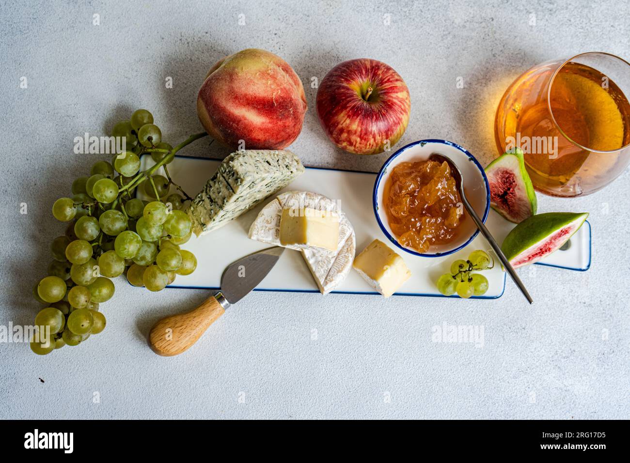 Von oben verschiedene leckere Snacks mit verschiedenen Käsesorten und Süßigkeiten, serviert auf Keramikteller mit Trauben, Apfel und Feigen auf dem Tisch Stockfoto