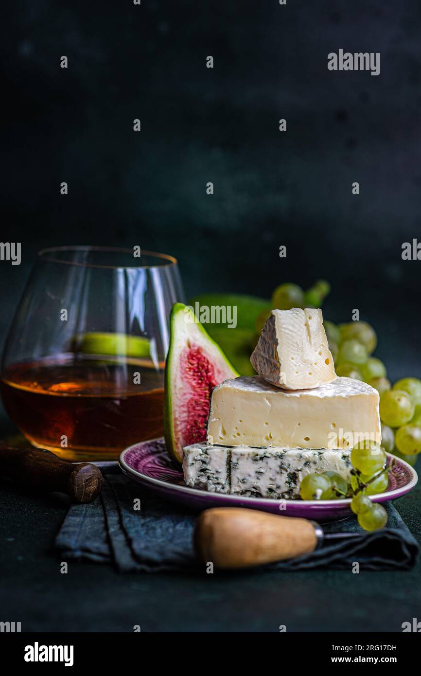 Verschiedene leckere Snacks mit Käse und serviert auf einem Teller mit Trauben, Feigen und Getränk Stockfoto