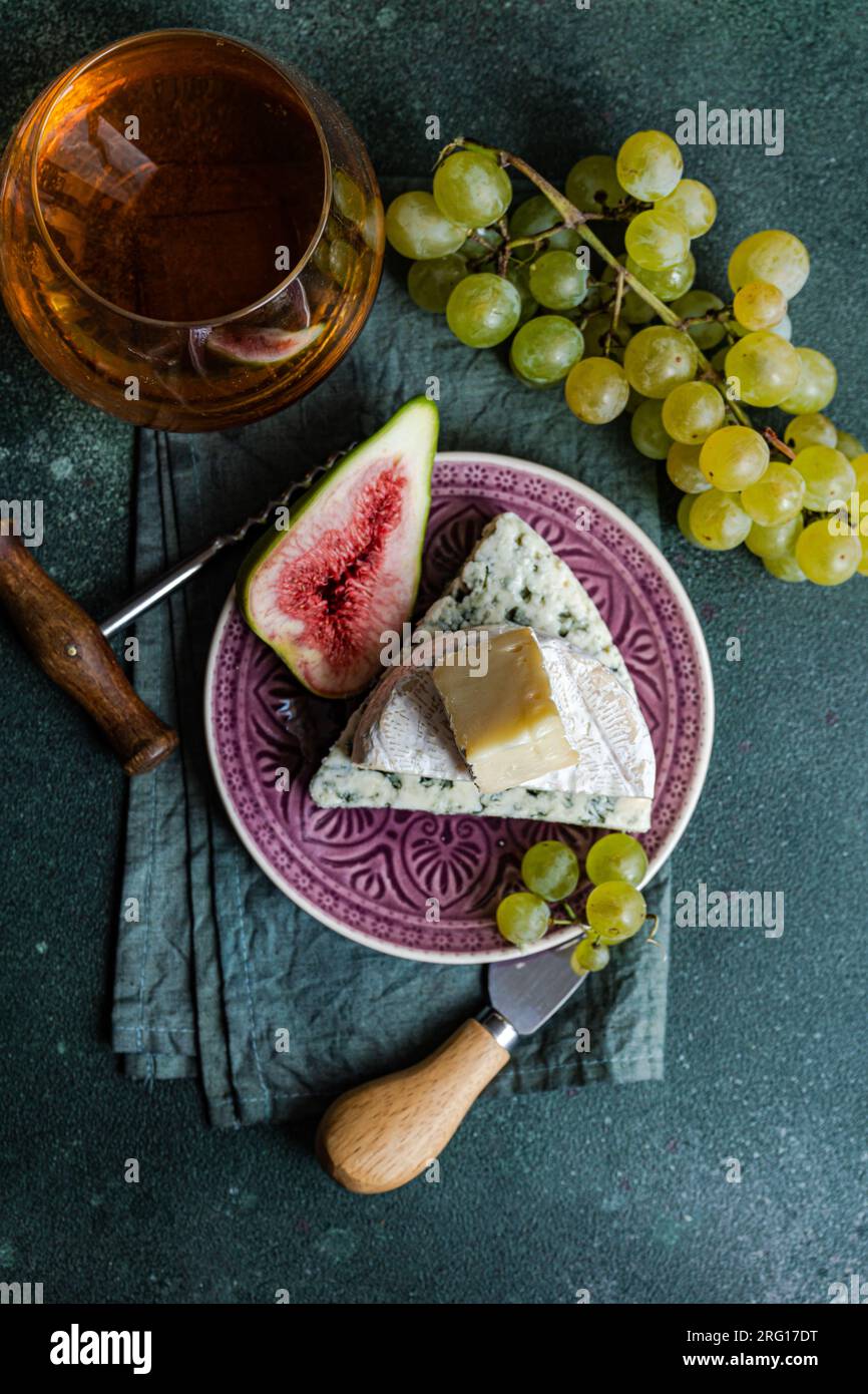 Von oben sortierte man leckere Snacks mit Käse und serviert auf einem Teller mit Trauben, Feigen und Getränk Stockfoto