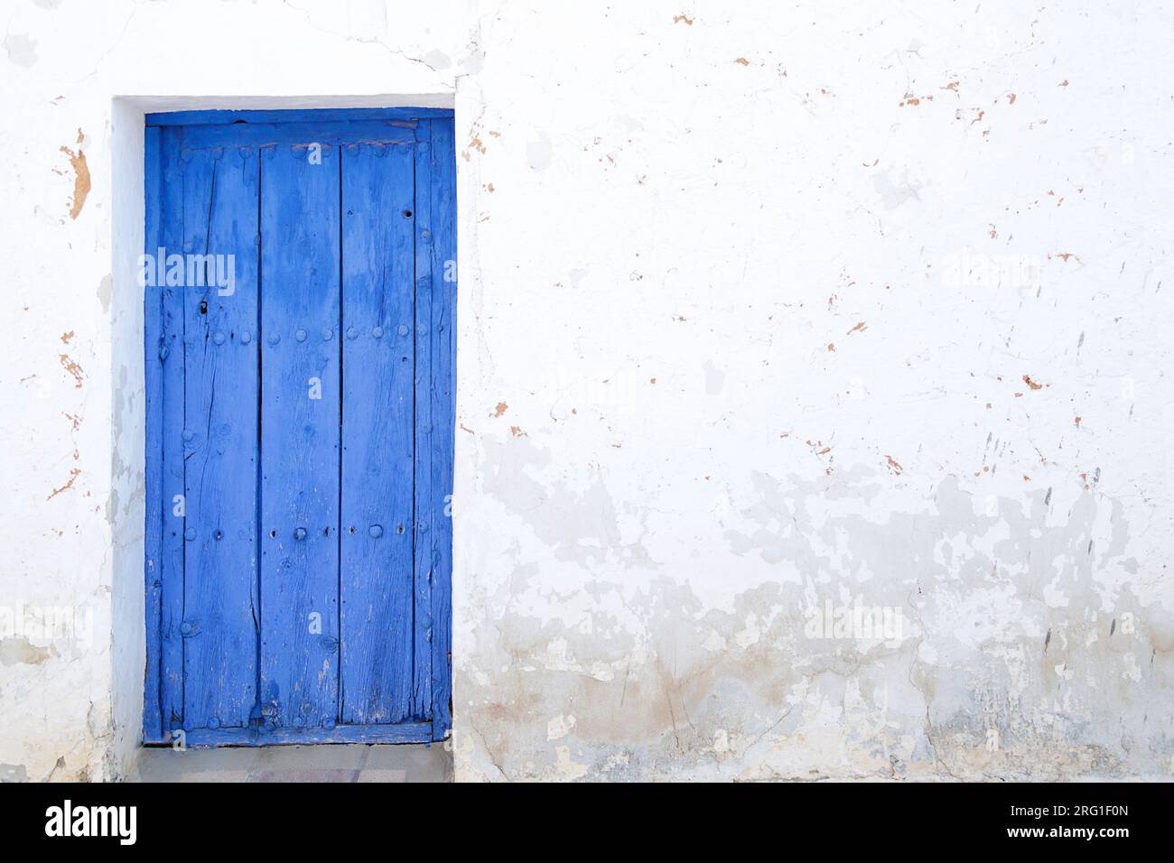Weiße Wand mit blauer Holztür Stockfoto