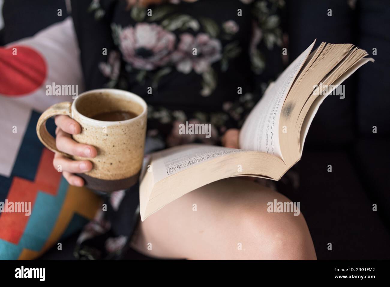 Nahaufnahme einer Frau, die Buch liest und Kaffeetasse hält Stockfoto