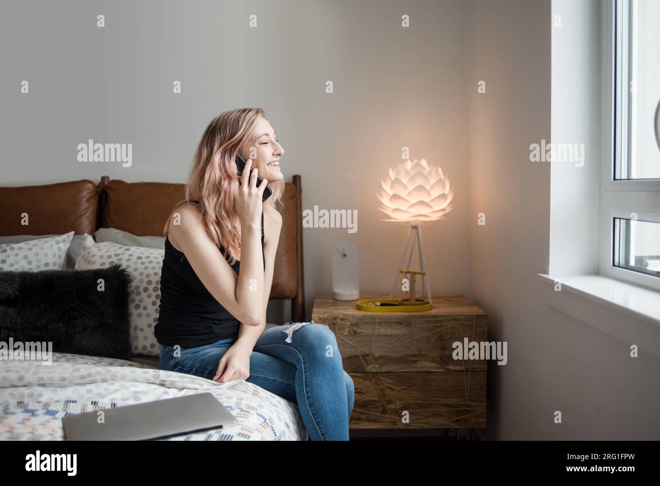 Eine Frau am Telefon, die im Schlafzimmer lacht Stockfoto