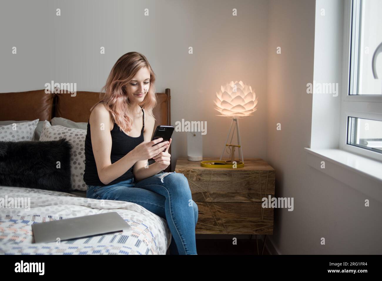 Frau, die im Bett sitzt und SMS auf dem Smartphone schreibt Stockfoto