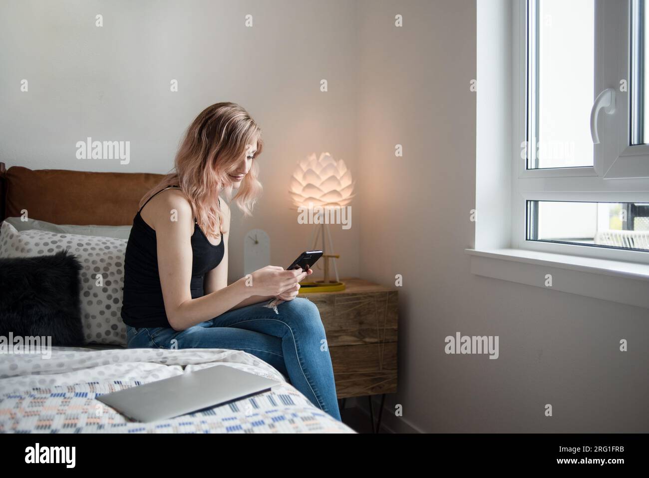 Frau, die im Schlafzimmer ein Smartphone benutzt Stockfoto