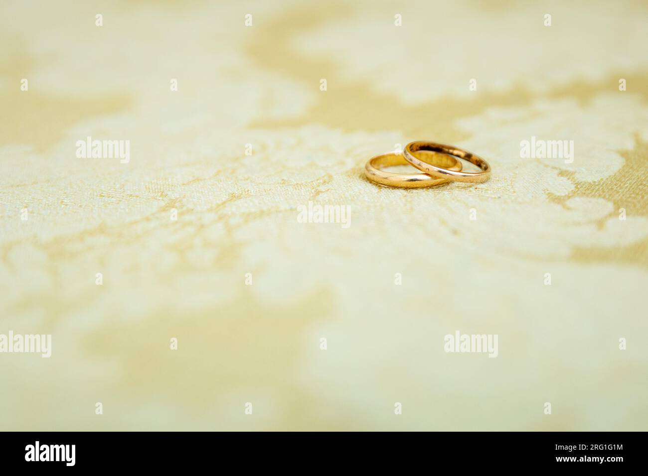 Detail mit goldenen Eheringen, einer übereinander, die die Liebe und Vereinigung eines Paares symbolisieren. Stockfoto