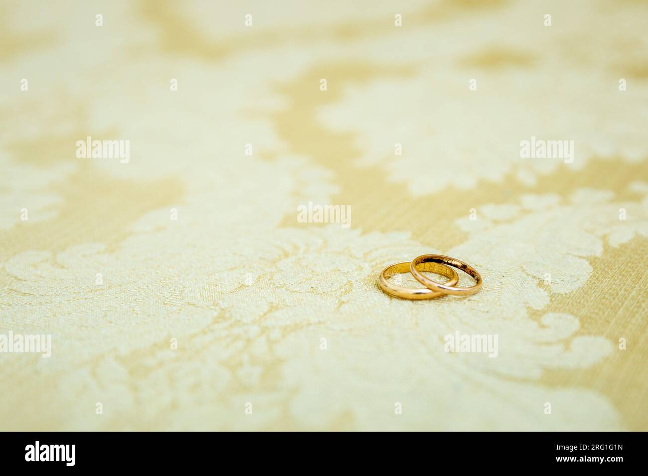 Detail mit goldenen Eheringen, einer übereinander, die die Liebe und Vereinigung eines Paares symbolisieren. Stockfoto