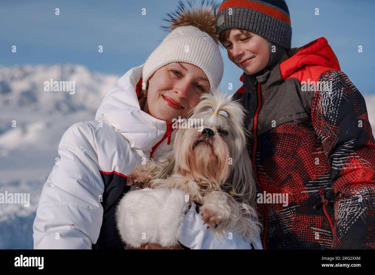 Mutter, Sohn und Shih-Tzu-Hund im Hintergrund der Winterberge Stockfoto