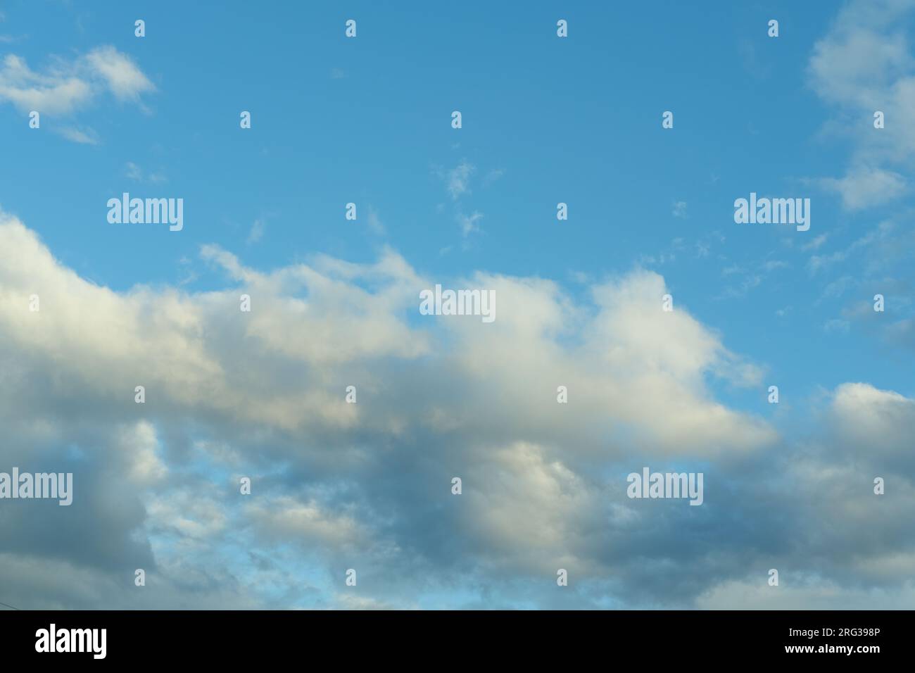 Blauer Himmel Hintergrund mit weißen flauschigen Cumulus Wolken. Panorama von weißen, flauschigen Wolken am blauen Himmel. Wunderschöner, riesiger blauer Himmel mit erstaunlichen verstreuten Stockfoto