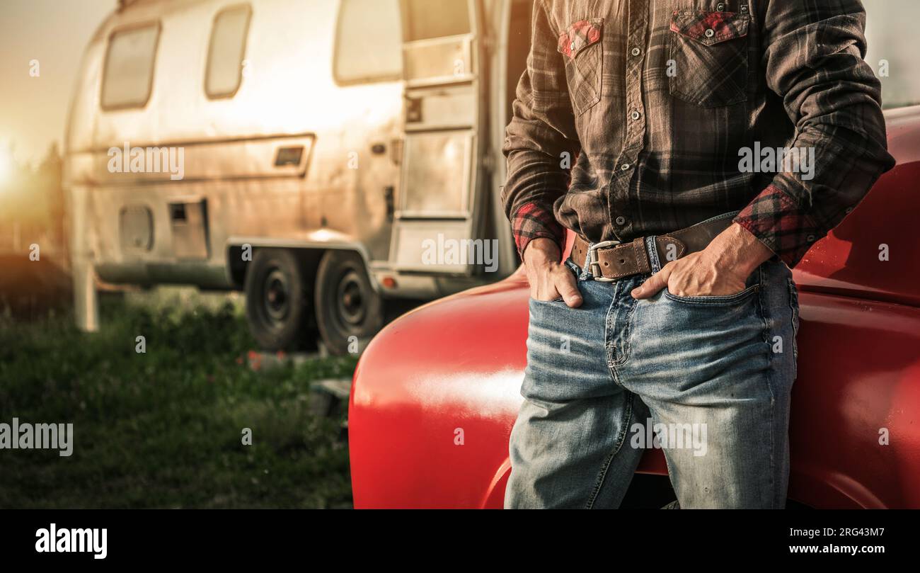 American West Cowboy mit Händen in den Hosentaschen bleibt neben seinem Truck und einem Reiseanhänger Stockfoto