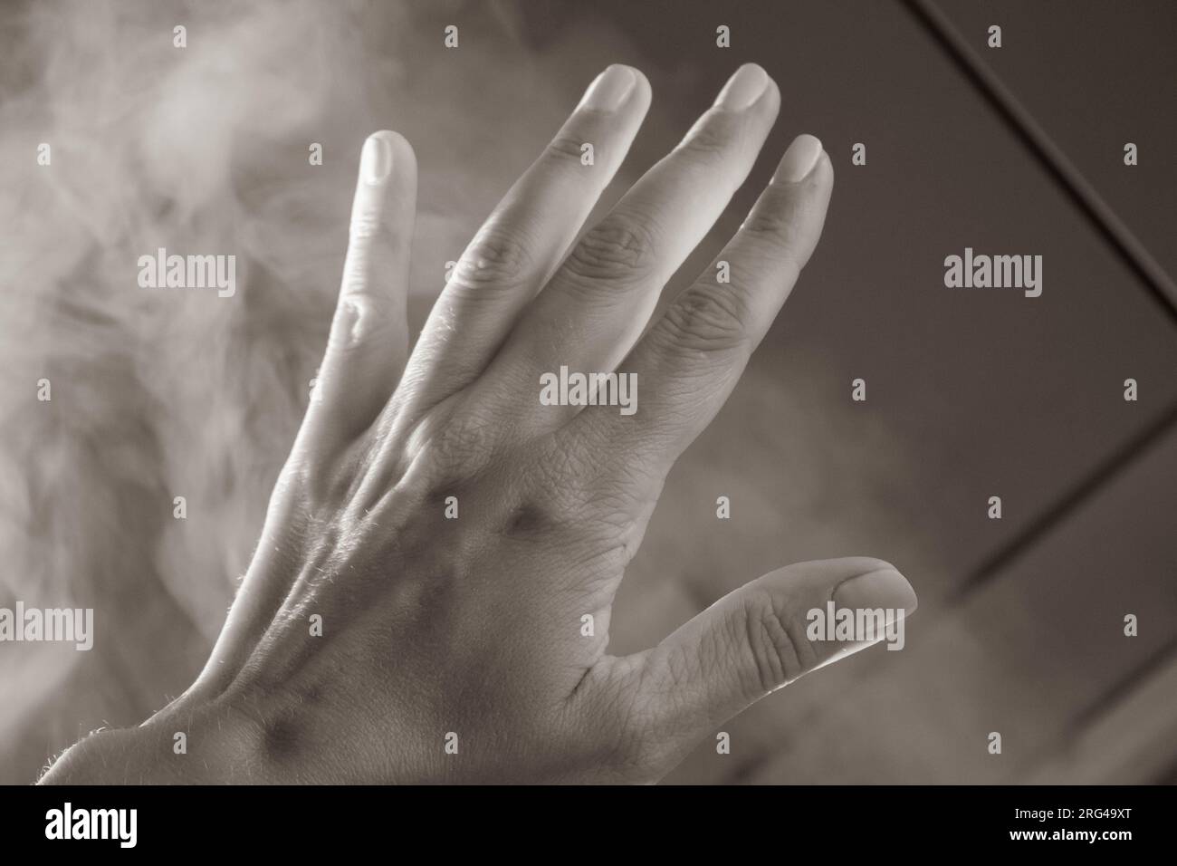 Öffnen Sie die Handfläche mit fünf Fingern im Rauch. Menschlicher Arm in natürlichem Licht mit Schatten. Hilfe-Geste. Opazitätskonzept. Frau Hand im Dunst. Hand in den Himmel. Stockfoto