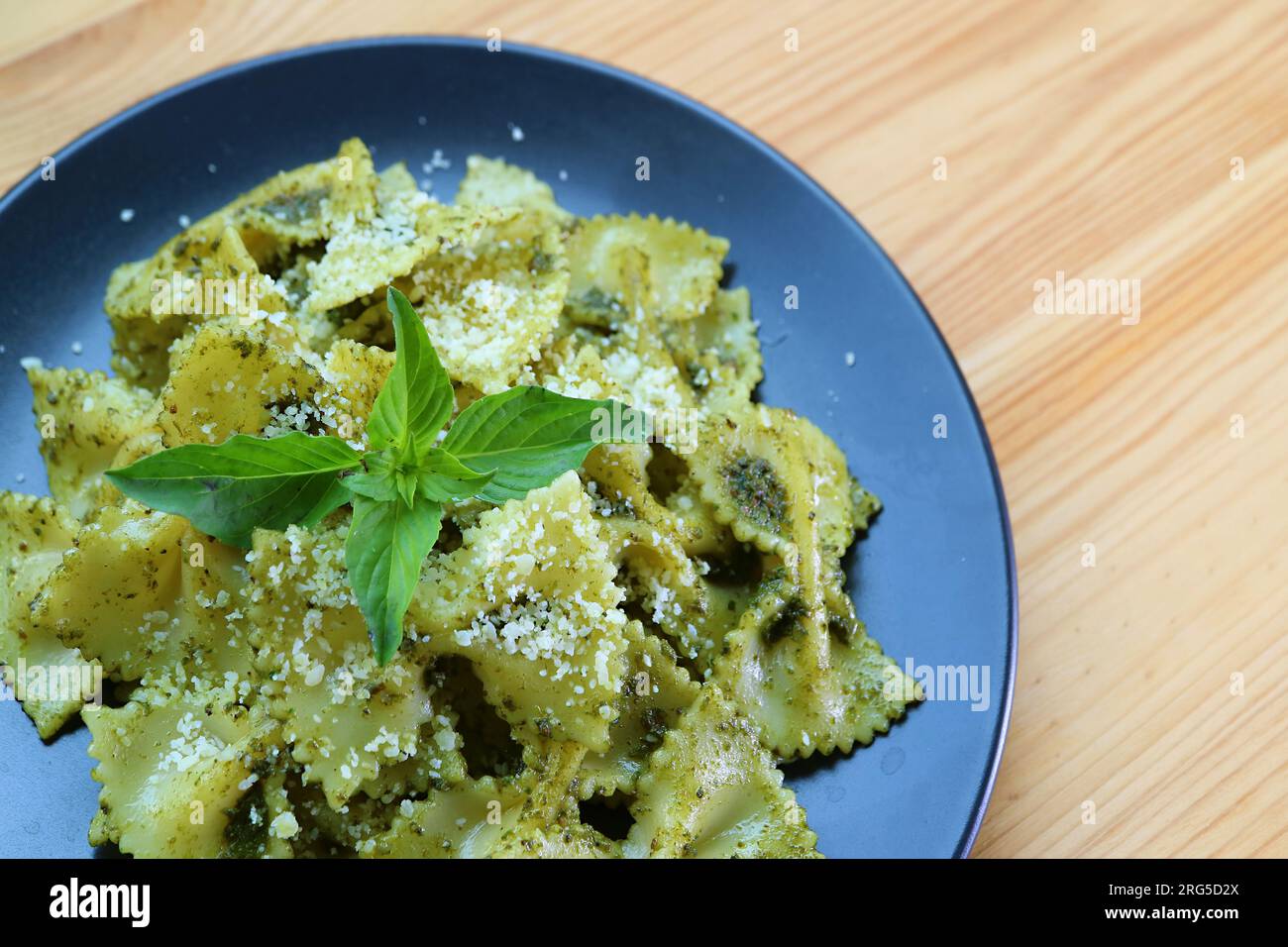Köstliche Pasta mit Fliege oder Farfalle in Pesto-Sauce, serviert auf einem Holztisch Stockfoto