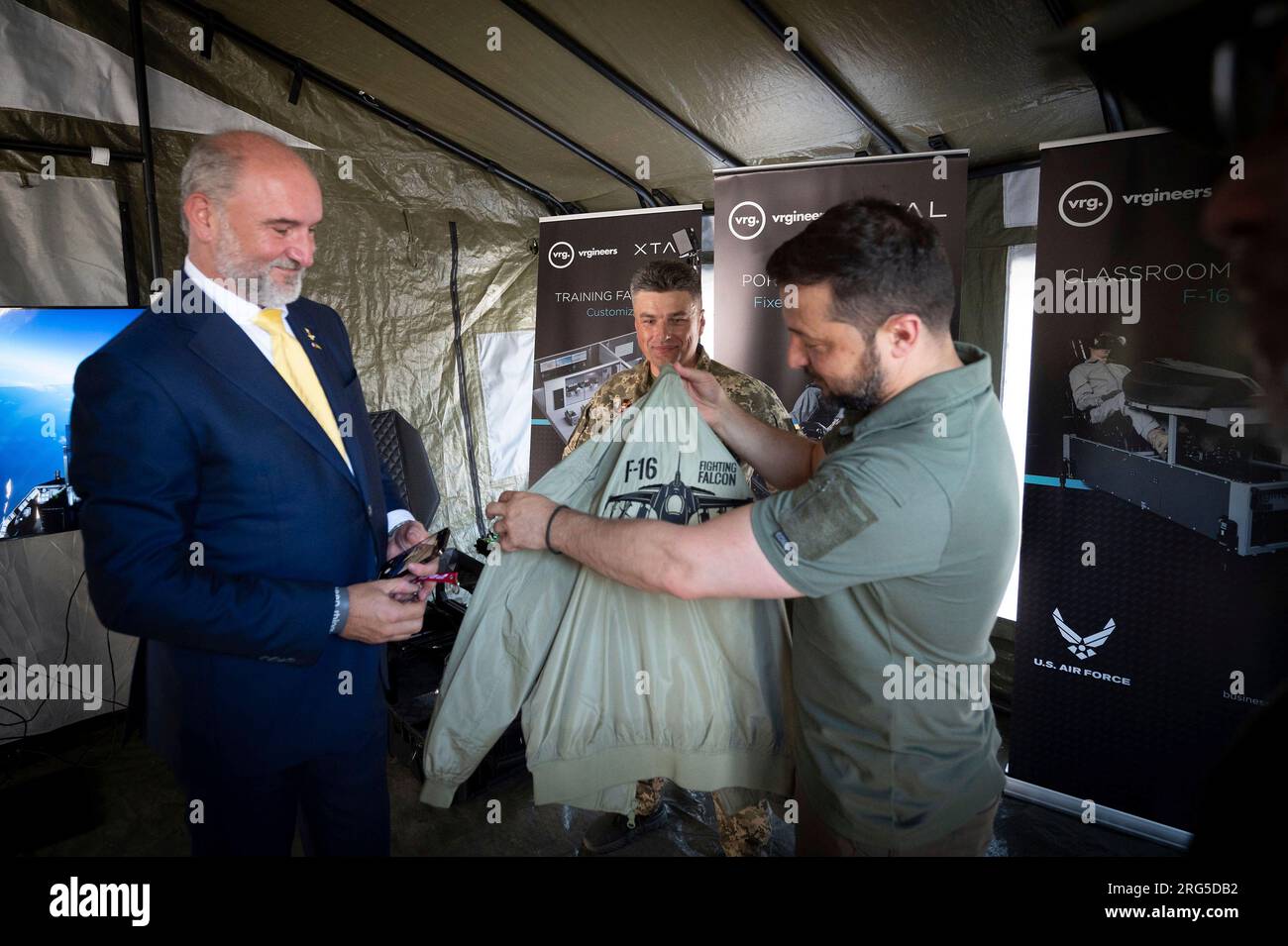 Kiew, Ukraine. 06. Aug. 2023. Der ukrainische Präsident Volodymyr Zelenskyy, Right, erhält eine Jacke mit dem Logo des F-16 Kampfflugzeugs Falcon, während er das Flugsimulationsübungssystem der Tschechischen Republik am Luftwaffentag, 6. August 2023 in Kiew, Ukraine, besucht. Kredit: Pool Photo/Pressestelle Des Ukrainischen Präsidenten/Alamy Live News Stockfoto