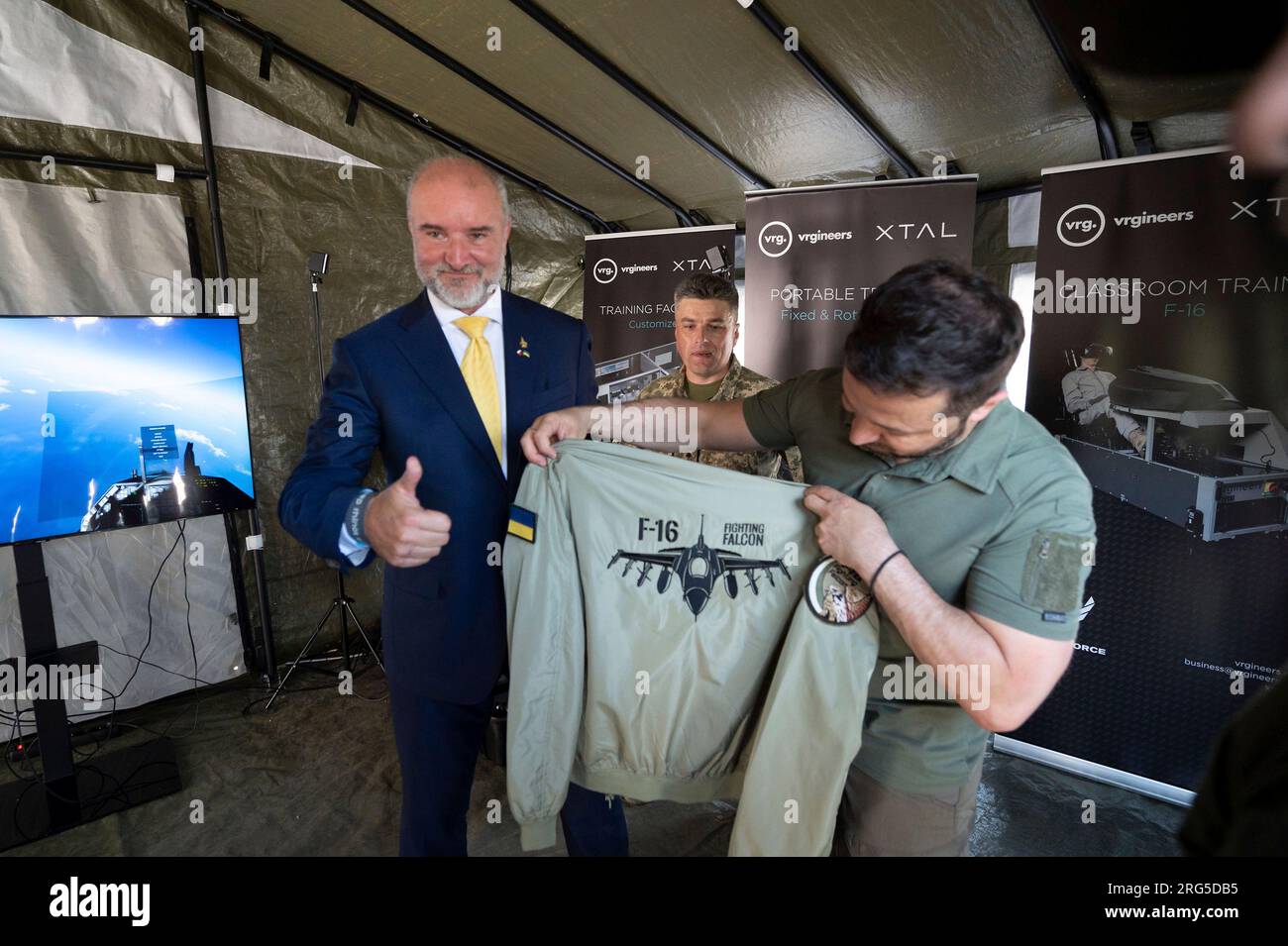 Kiew, Ukraine. 06. Aug. 2023. Der ukrainische Präsident Volodymyr Zelenskyy, Right, erhält eine Jacke mit dem Logo des F-16 Kampfflugzeugs Falcon, während er das Flugsimulationsübungssystem der Tschechischen Republik am Luftwaffentag, 6. August 2023 in Kiew, Ukraine, besucht. Kredit: Pool Photo/Pressestelle Des Ukrainischen Präsidenten/Alamy Live News Stockfoto