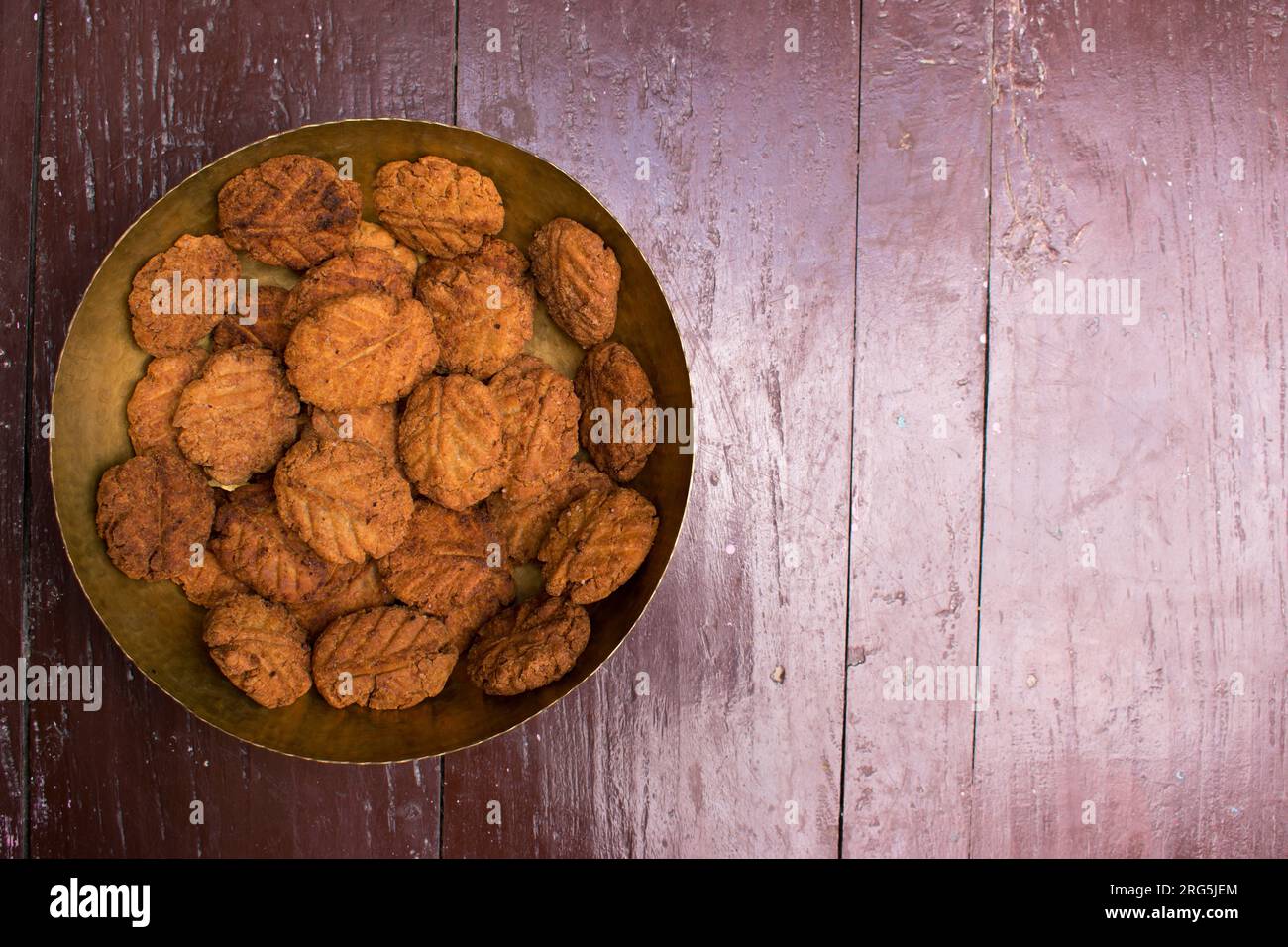 Thekua, ein indisches süßes Gericht oder Snacks auf einer Messingplatte mit Schimmel auf einem Holztisch. Es ist beliebt in bihar und jharkhand .Prashad in chhath Festival Stockfoto