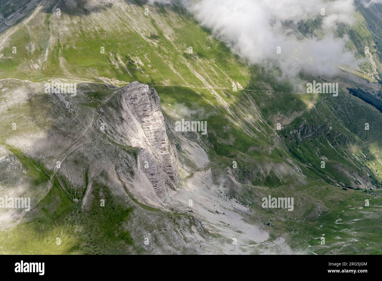 Luftlandschaft, aus einem Segelflugzeug, mit steilen Klippen an kargen östlichen Hängen der Vettore Range und Meeresbrise Wolken, die von Norden in heller Su aufgenommen werden Stockfoto