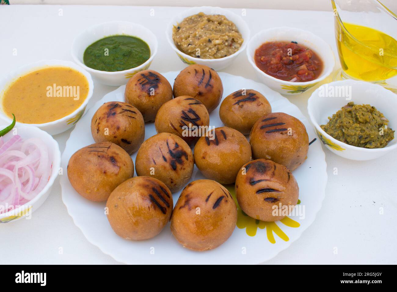Litti auf weißem Teller mit Tomate, Brinjal, Kartoffel, spitzem Gaurd und Korianderchutney oder Schokolade und Ghee. Es ist beliebt in Bihar, Uttar Pradesh Stockfoto