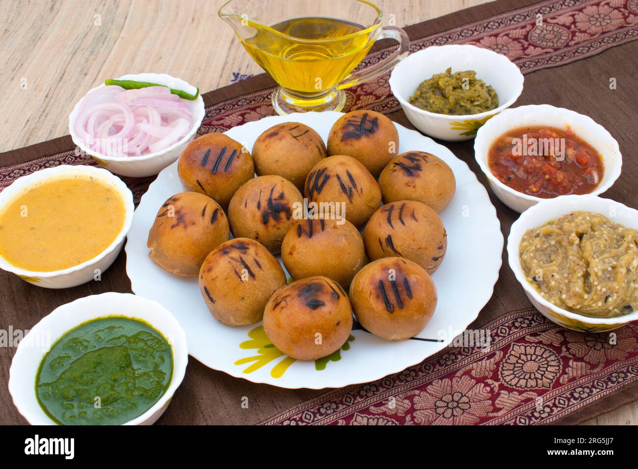 Litti auf weißem Teller mit Tomate, Brinjal, Kartoffel, spitzem Gaurd und Korianderchutney oder Schokolade und Ghee. Es ist beliebt in Bihar, Uttar Pradesh Stockfoto