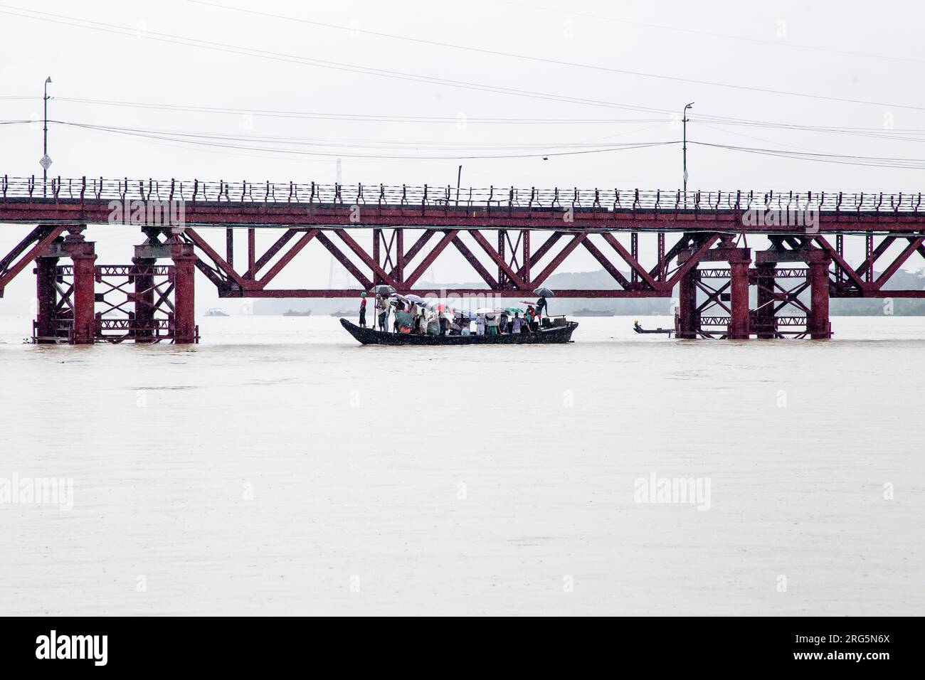 In der Regenzeit, in der die Kalurghat-Brücke drei Monate lang unzugänglich war, stehen die Menschen vor Not, da sie auf kleine Boote angewiesen sind, um den Fluss zu überqueren. Der ständige Kampf, durch das Wasser zu navigieren, erzeugt ein Gefühl von Leid und Unannehmlichkeiten für die betroffenen Gemeinden. Trotz der Herausforderungen ist ihre Widerstandsfähigkeit deutlich spürbar, da sie die Schwierigkeiten ertragen, ihr Ziel zu erreichen. Chittagong, Bangladesch. Stockfoto
