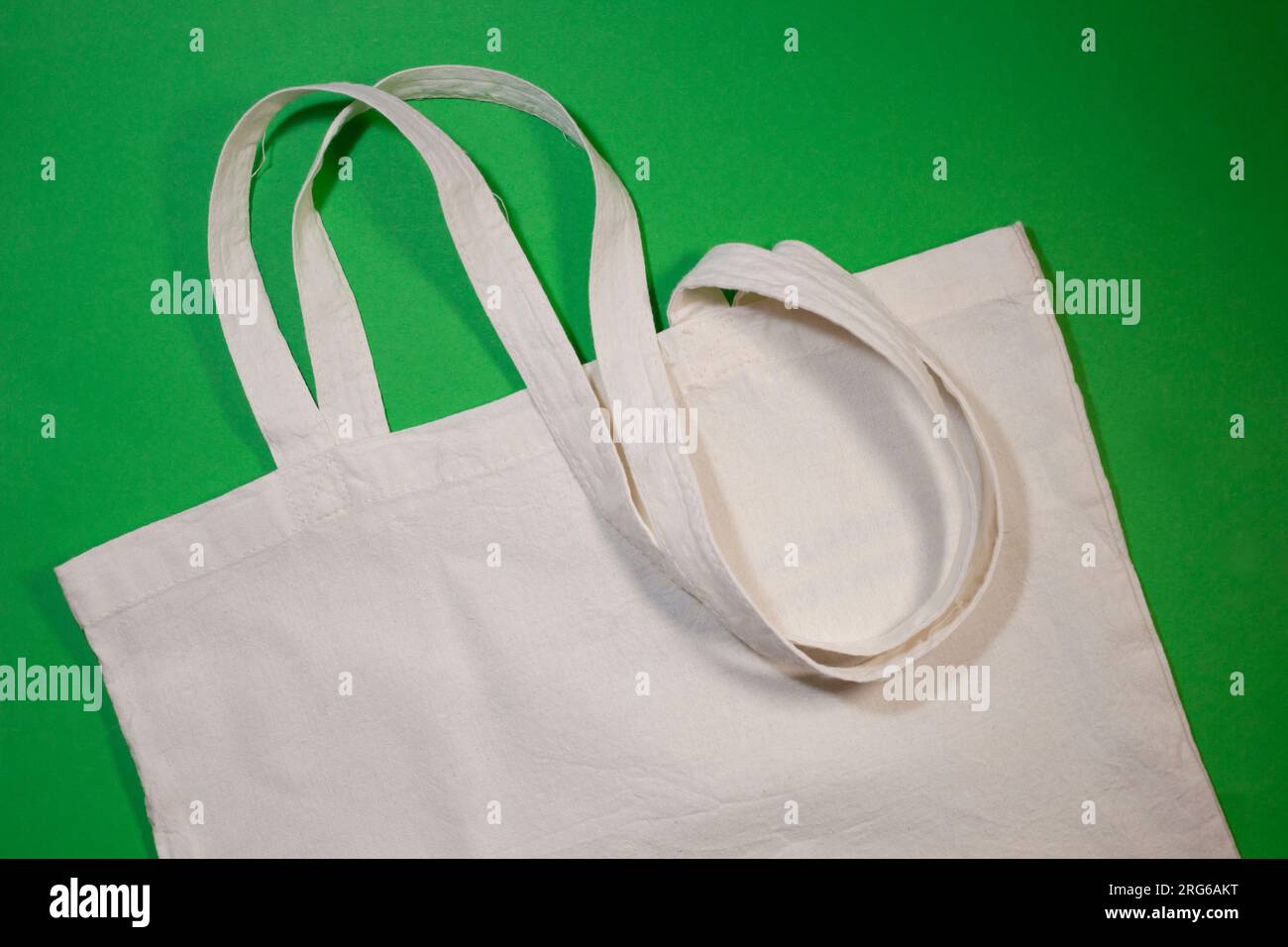 Weiße Baumwolle- oder Netztasche auf grünem Hintergrund. Kein Abfall, kein Kunststoff, umweltfreundliches Einkaufen, Recycling-Konzept. Stockfoto