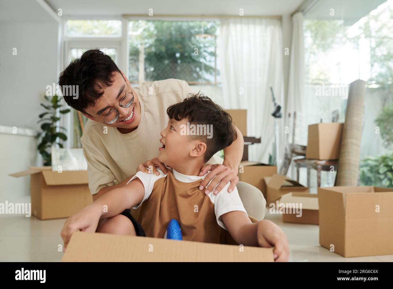 Vater und Sohn sitzen in einer Pappschachtel und spielen zu Hause zusammen Stockfoto