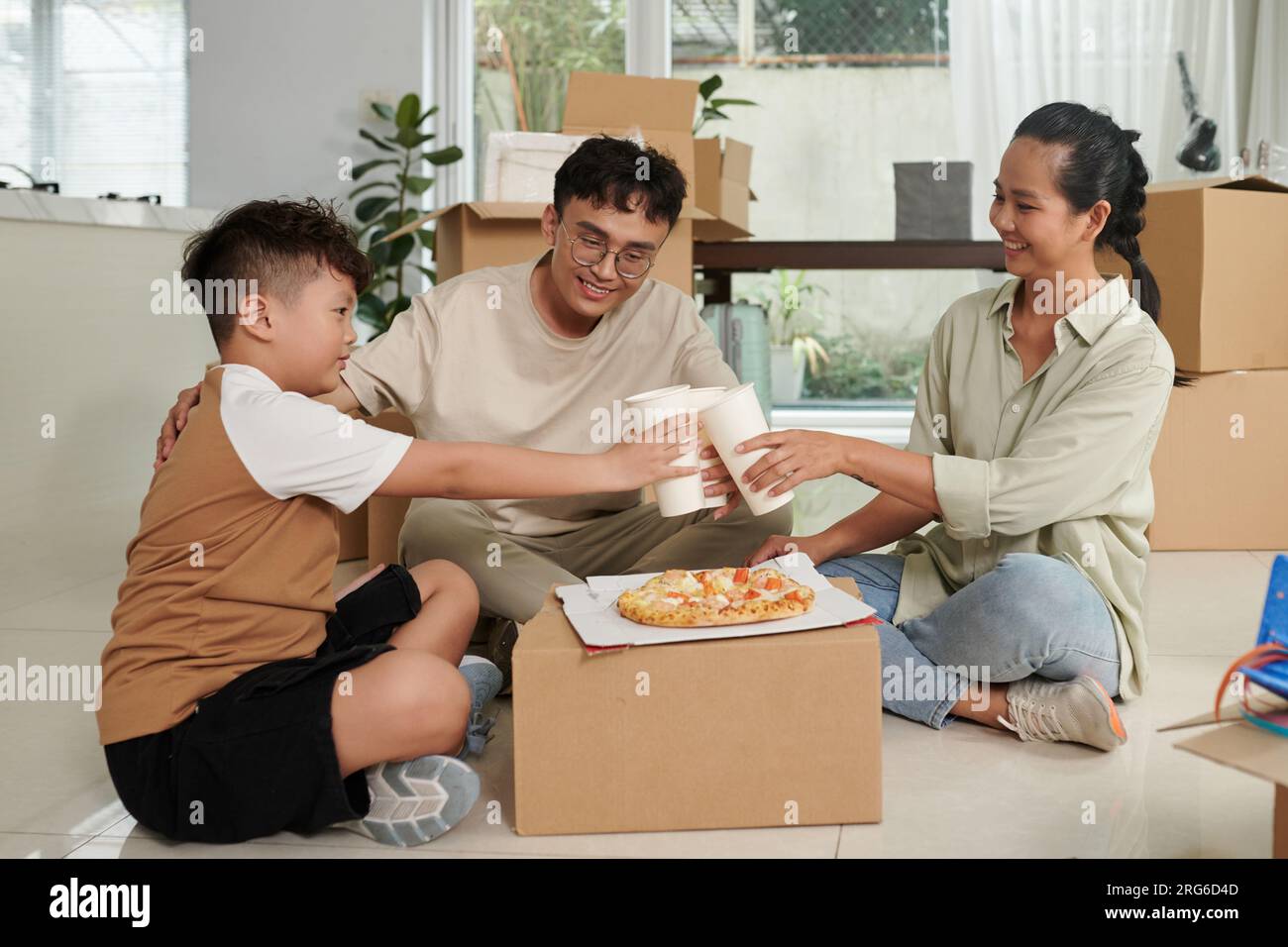 Familientoast mit Gläsern alkoholfreier Getränke auf einem improvisierten Papptisch mit Pizza Stockfoto