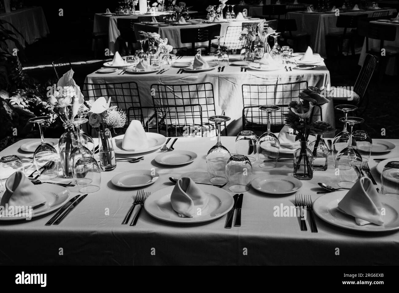 Wunderschön angelegte Tische mit Gläsern, Besteck und Geschirr für eine große Feier vorbereitet. Schwarzweißfotografie. Stockfoto