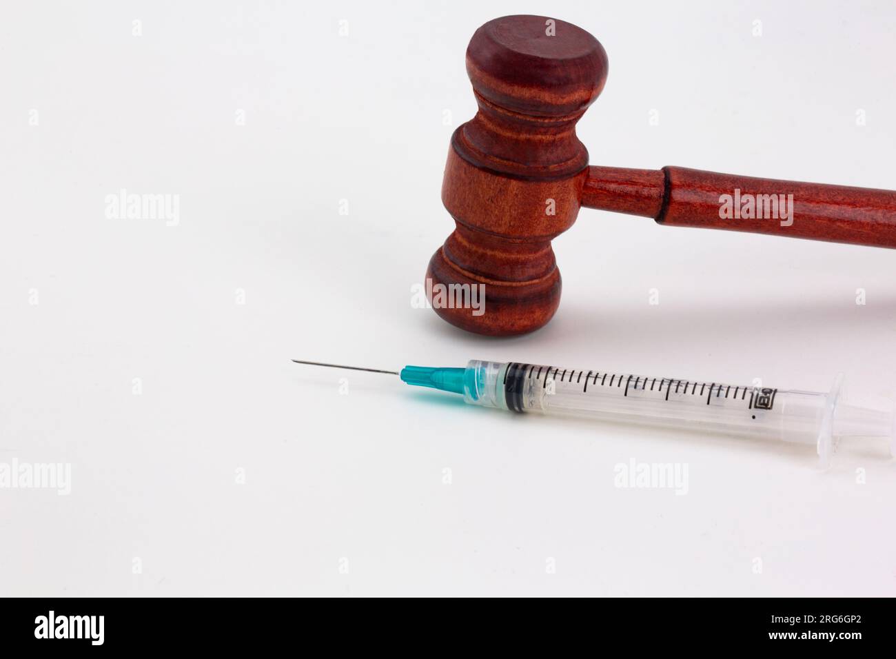 Hammer und Spritze auf weißem Hintergrund deuten auf konzeptionelle Verbindungen von medizinischen und rechtlichen Fragen hin Stockfoto