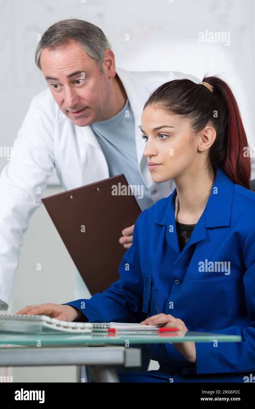 Lehrerin, die Schülerinnen mit dem Computer hilft Stockfoto