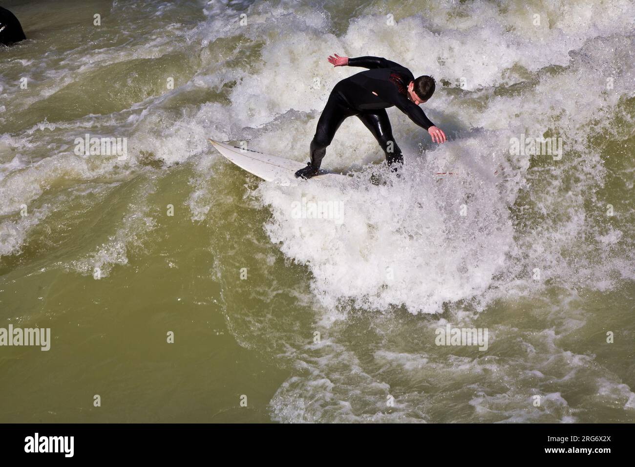 MÜNCHEN, DEUTSCHLAND - 07. APRIL: Surfer surft am Isar in riesigen Wellen zur Saisoneröffnung an der Wittelsbacher Brücke im Herzen Münchens am April Stockfoto