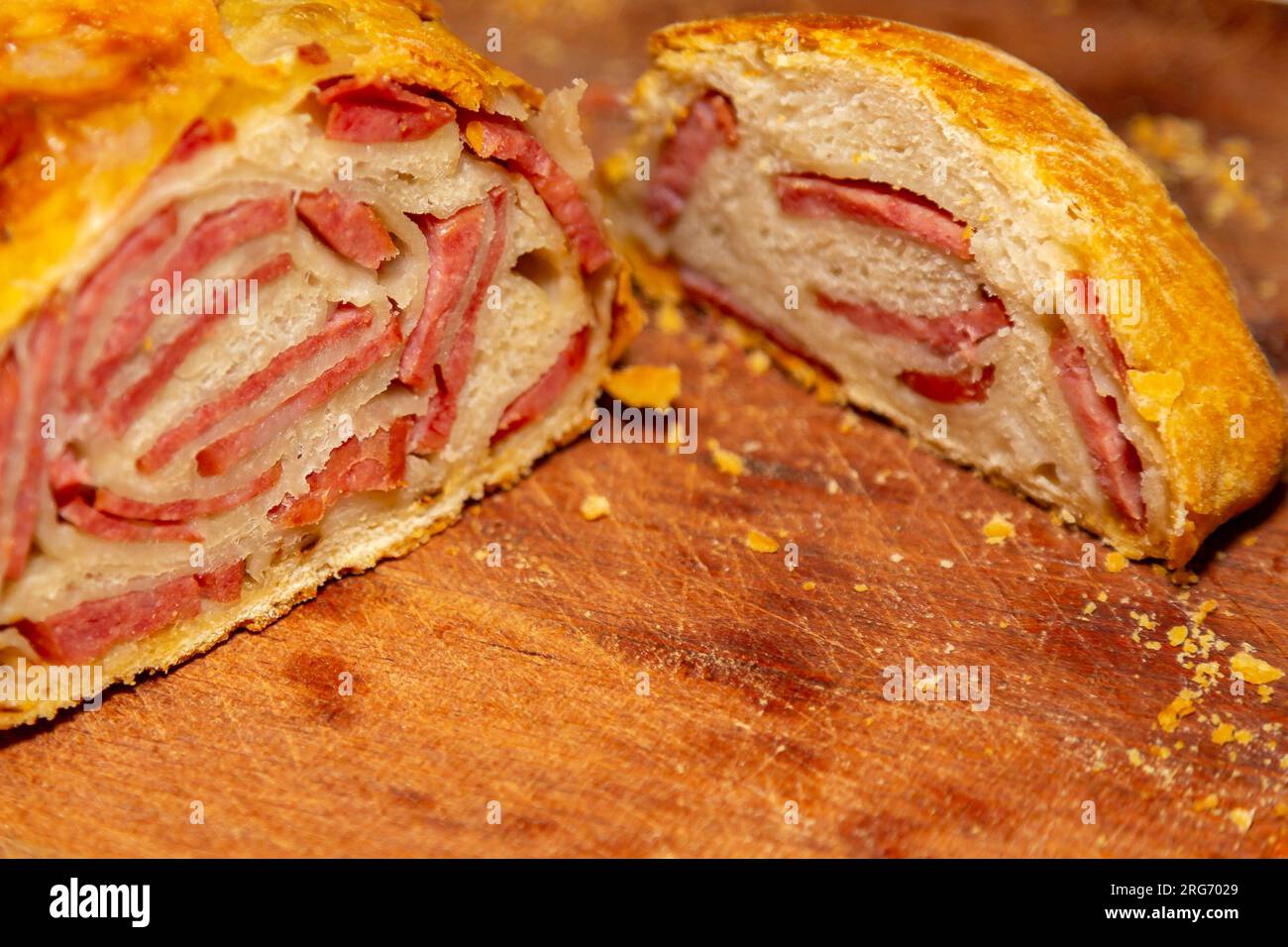 Schneiden eines Pepperoni-Brots auf eine rustikale Oberfläche mit selektivem Fokus Stockfoto