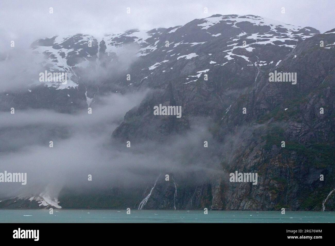Wasserfälle, die aus den Bergen in die Glacier Bay strömen Stockfoto