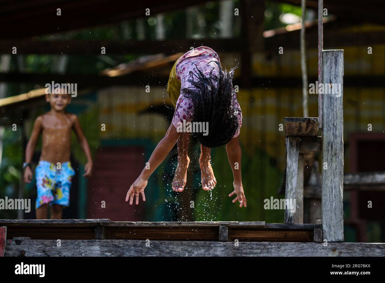 Belem, Brasilien. 07. Aug. 2023. Kinder von der Insel Combu spielen auf dem Guama River. Auf der gegenüberliegenden Uferseite befindet sich die Stadt Belem. Die Menschen leben am Ufer von Guama in hölzernen Hütten, die als „Palafitas“ bekannt sind. Dort leben sie vom Verkauf der Früchte der Kohlpalme, von Kakao, Fisch und Tourismus. Ab Dienstag werden die Staats- und Regierungschefs der südamerikanischen Amazonasländer über den Schutz des Regenwaldes in Belem, Brasilien, diskutieren. Kredit: Filipe Bispo Vale/dpa/Alamy Live News Stockfoto