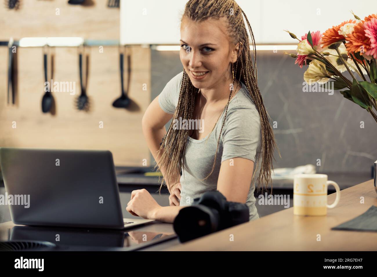 Junge Frau mit Boxgeflecht ist sehr auf Fotografie bedacht. Mit einer DSLR und einem Laptop experimentiert sie in ihrer Küche. Techniken zu beherrschen ist entscheidend Stockfoto