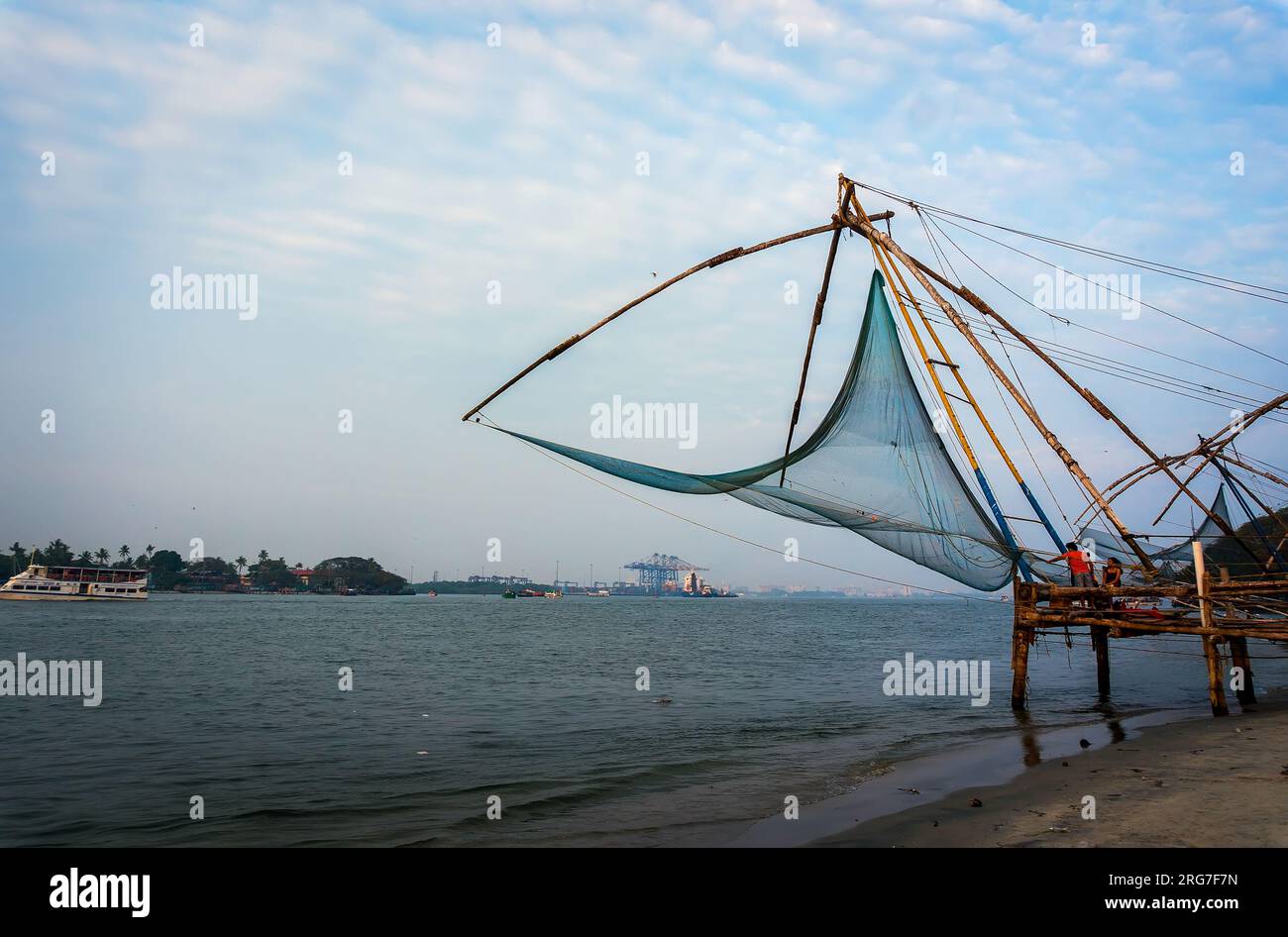 Chinesische Fischernetze und kleines Schiff bei dramatischem Sonnenuntergang am Himmel. Chinesische Fischernetze. Vembanad Lake, Kerala, Südindien Stockfoto