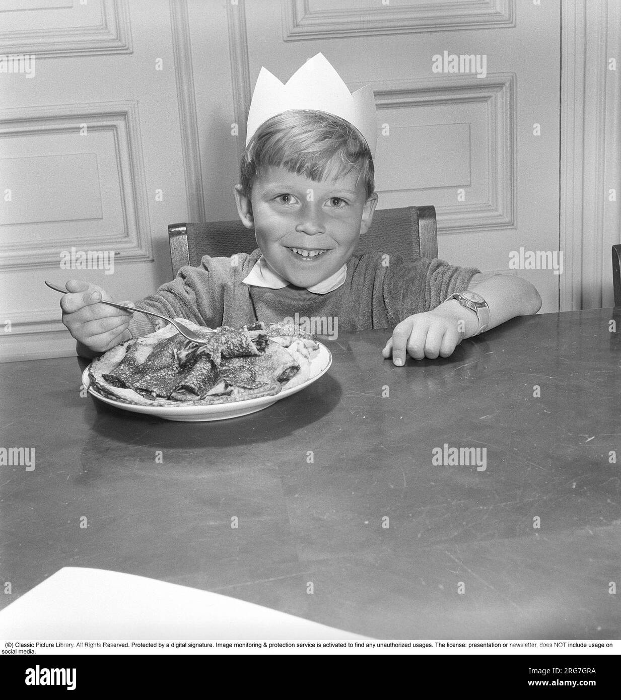 Der Junge in den 1950er. Lächelnd, wenn man vor einem Teller mit Pfannkuchen und einem auf der Gabel saß, bereit zum Essen. Schweden 1953 Ref. BL109-10 Stockfoto