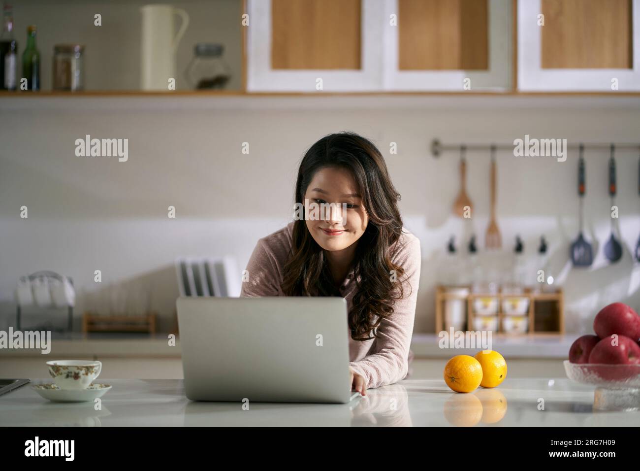 Junge asiatische Geschäftsfrau, weibliche Freiberuflerin, die zu Hause in der Küche mit einem Laptop arbeitet Stockfoto