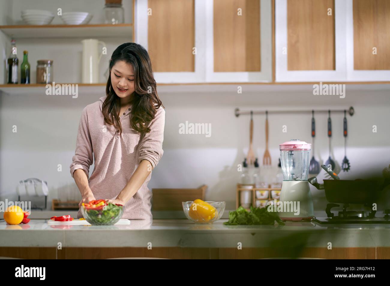 Junge asiatische Hausfrau, die zu Hause Salat in der Küche macht Stockfoto