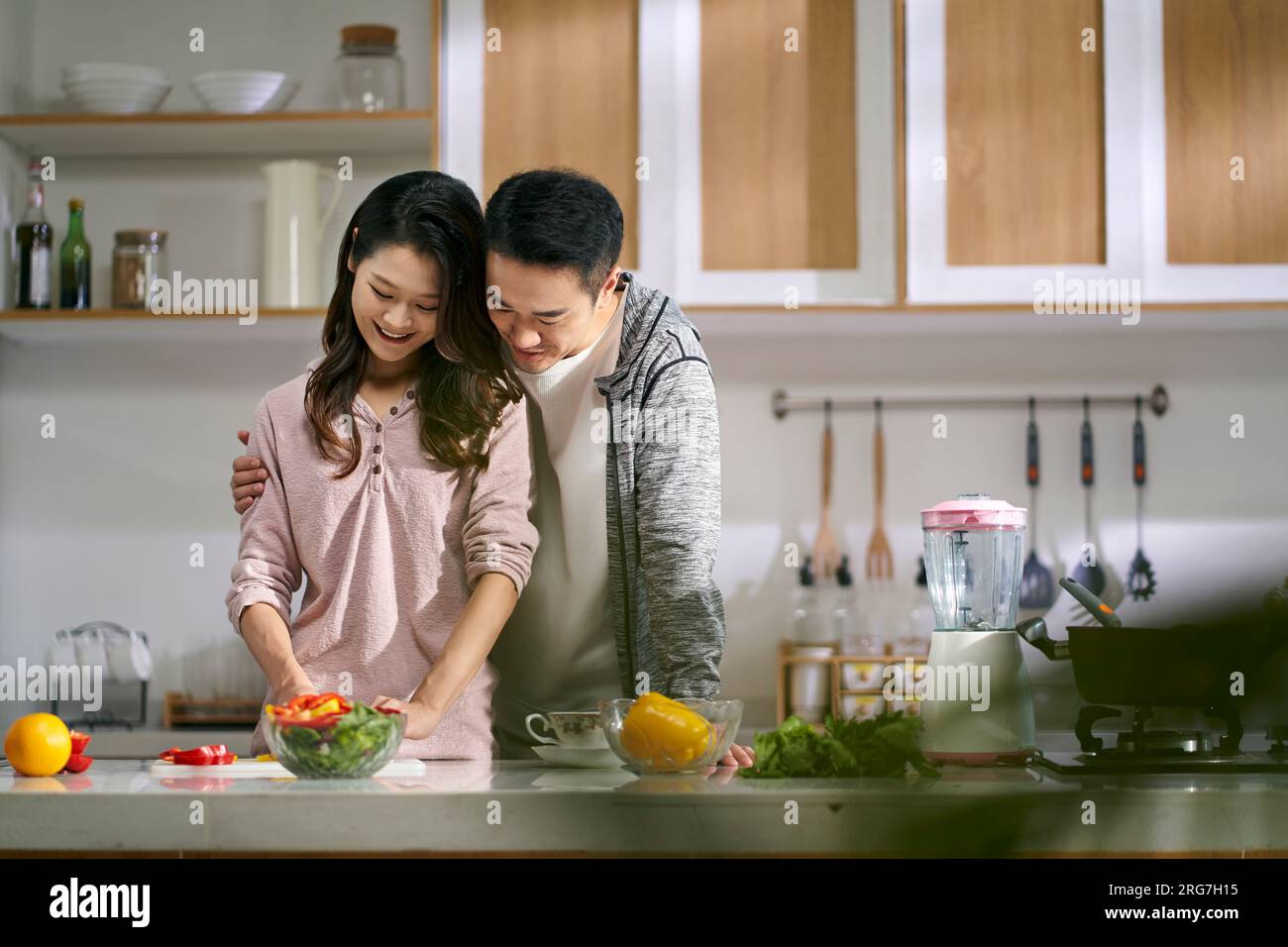 Glückliches, liebevolles junges asiatisches Paar, das zu Hause in der Küche zusammen Essen zubereitete Stockfoto